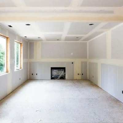 Unfinished living room with taped drywall seams, recessed ceiling lights, and a framed fireplace opening